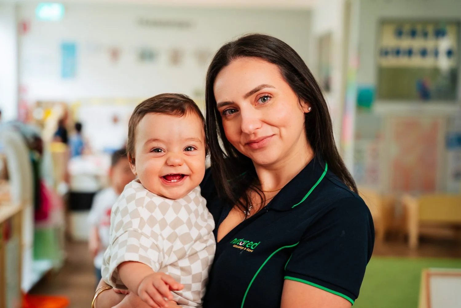 A Nurtured Education & Care educator holding a smiling child